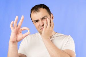 man in pain holding tooth