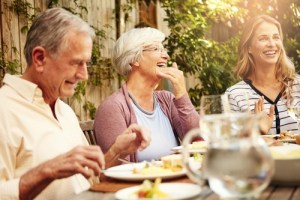 man and two woman eating meal and smiling 